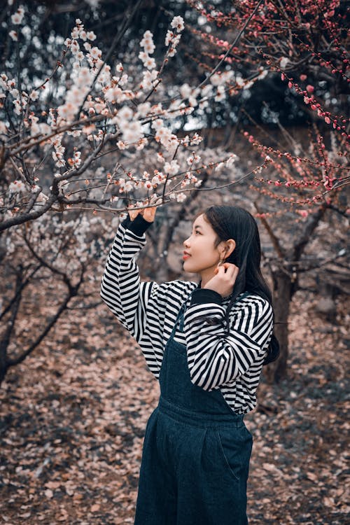 A Woman in Black and White Striped Long Sleeve Shirt Standing Under Cherry Blossom Tree