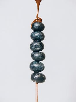Close-up of blueberries stacked on skewer with chocolate drizzle. Perfect for dessert ideas.