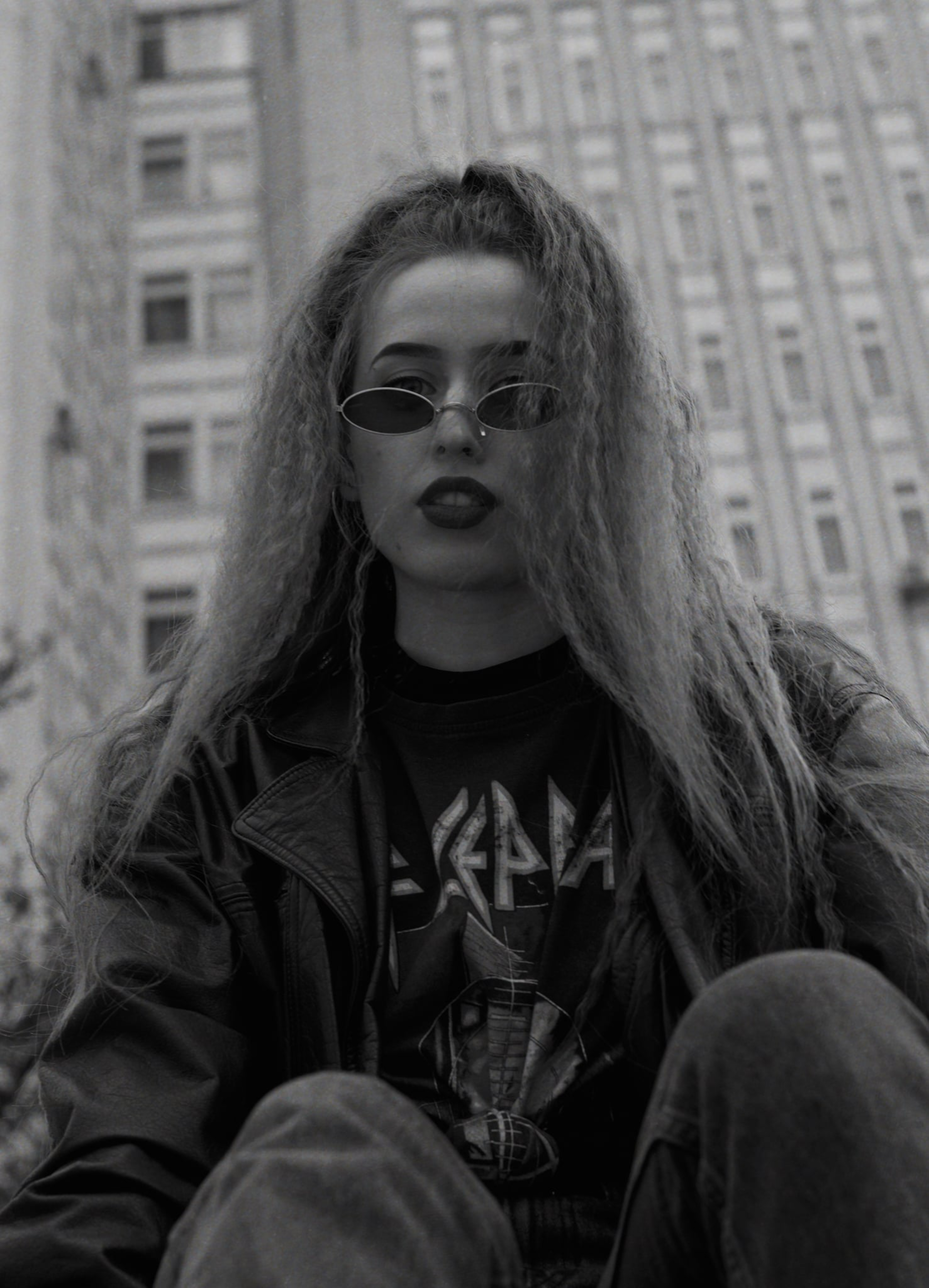 Stylish woman wearing a jacket and sunglasses in an urban setting.