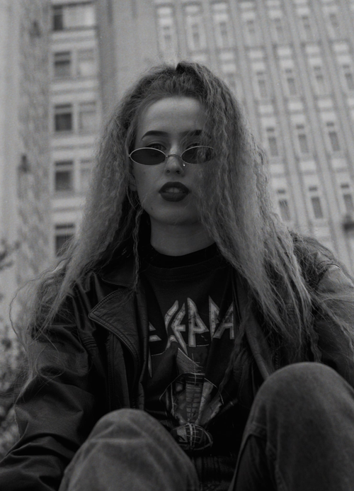 Free Stylish woman wearing a jacket and sunglasses in an urban setting. Stock Photo