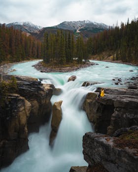Discover the serene beauty of a waterfall in Jasper, Alberta with turquoise waters and lush forests.