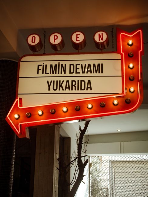 Vintage style illuminated sign with arrow indicating direction indoors.