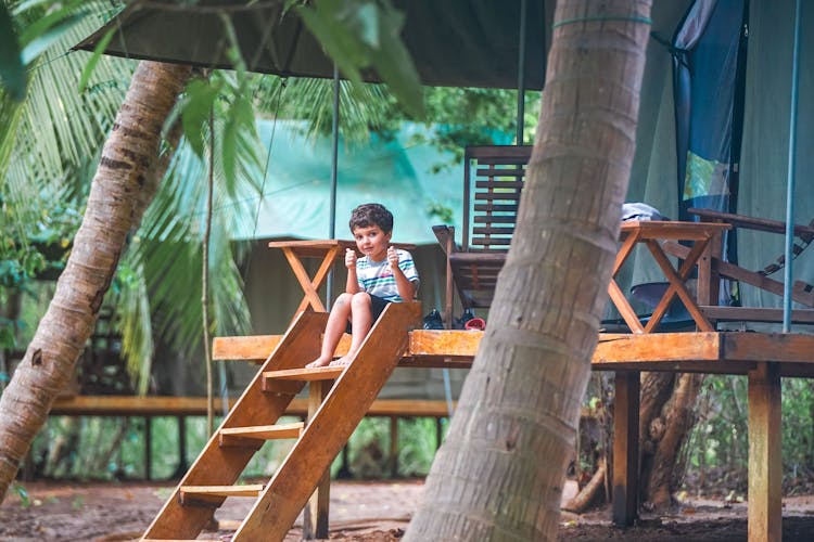 Cute Boy Sitting On Steps In Jungle 