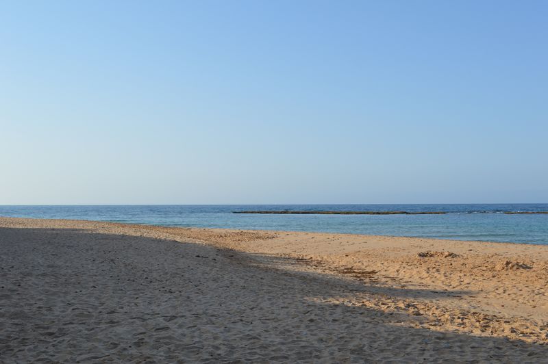 Golden sandy beach meeting a calm clear sea under a bright blue sky