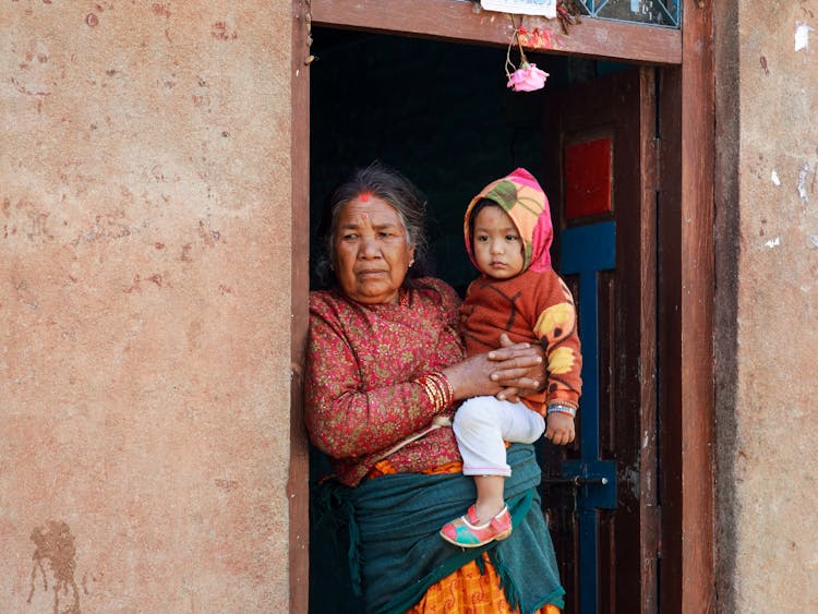 Woman Holding A Baby In A Doorway 