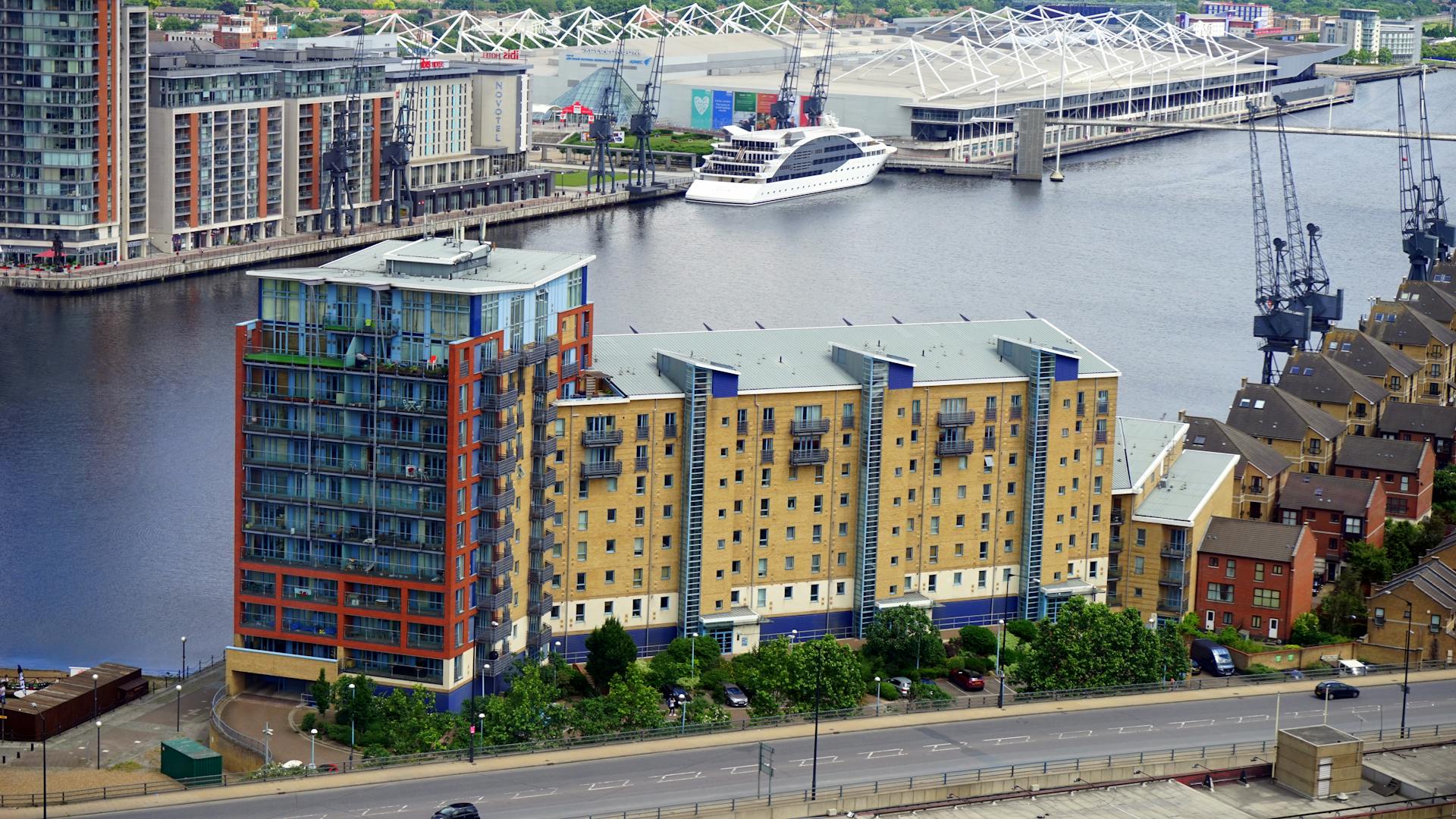A scenic view of contemporary buildings along the River Thames with a docked ship.
