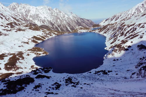 High-angle View of Body of Water in Between Snow-covered Mountain Range