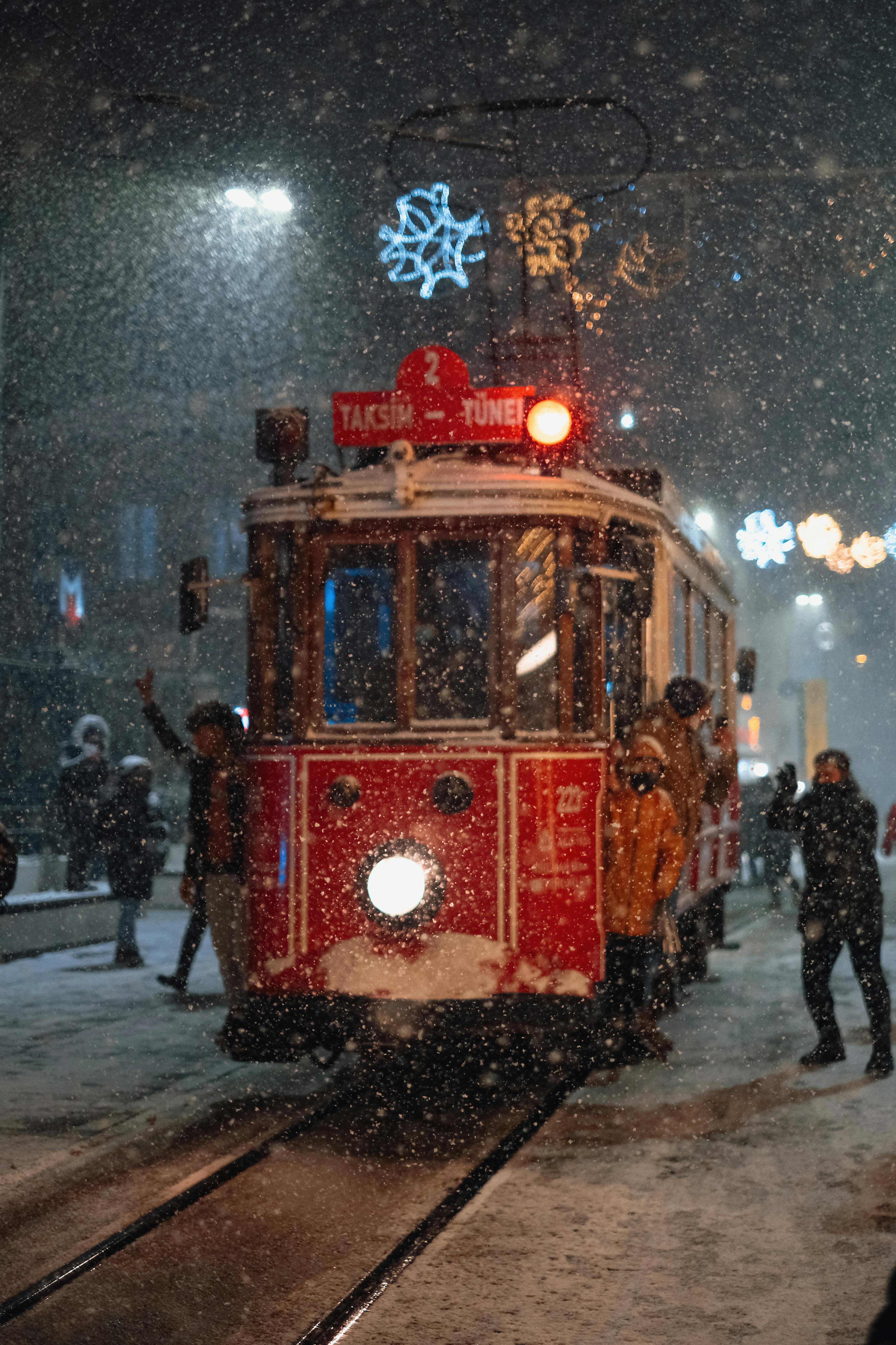 Historic tram in snowy Istanbul night with festive lights in Taksim Square, capturing winter magic.