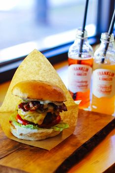Delicious cheeseburger with fresh vegetables and drinks, perfect for a satisfying meal.