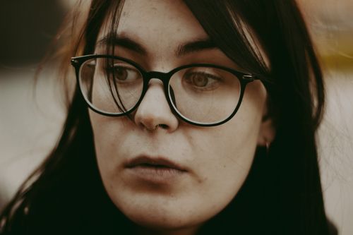Free Close-up portrait of a young woman with glasses in a thoughtful expression. Stock Photo
