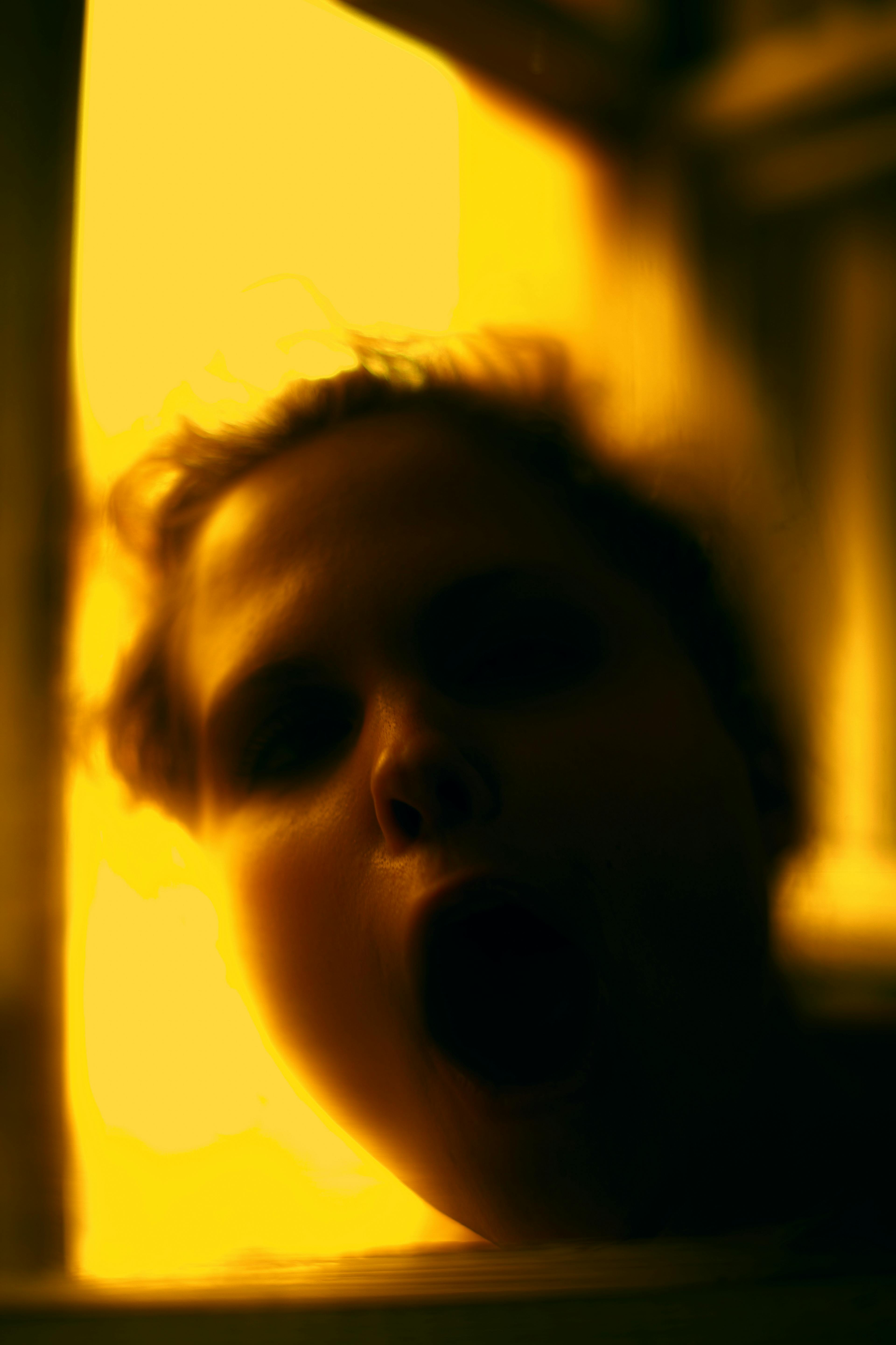 A blurry portrait capturing a person's surprised expression in warm lighting.