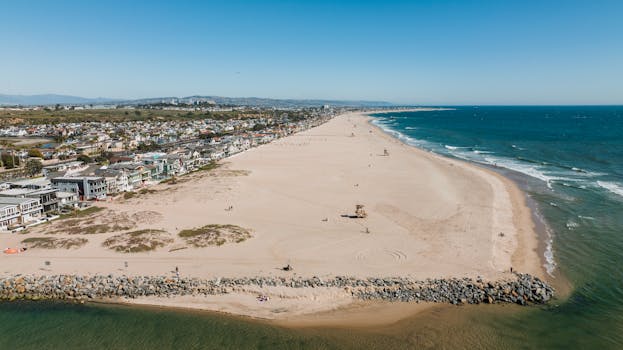 Aerial view of Huntington Beach showcasing sandy shores and coastal homes under a clear sky.