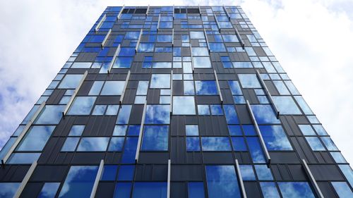 Free Low angle view of a modern glass skyscraper reflecting clouds. Futuristic urban architecture. Stock Photo