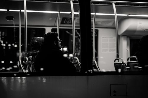 Free Grayscale image of passengers sitting inside a bus at night, viewed from outside. Stock Photo
