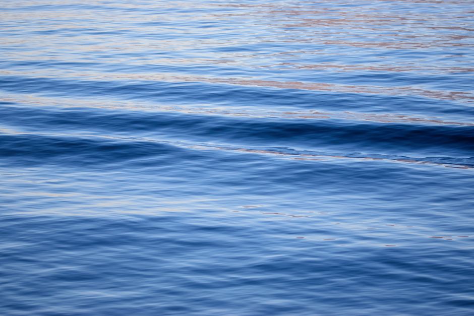 Close-up view of calm ocean waves reflecting sunlight, creating a serene and peaceful scene.
