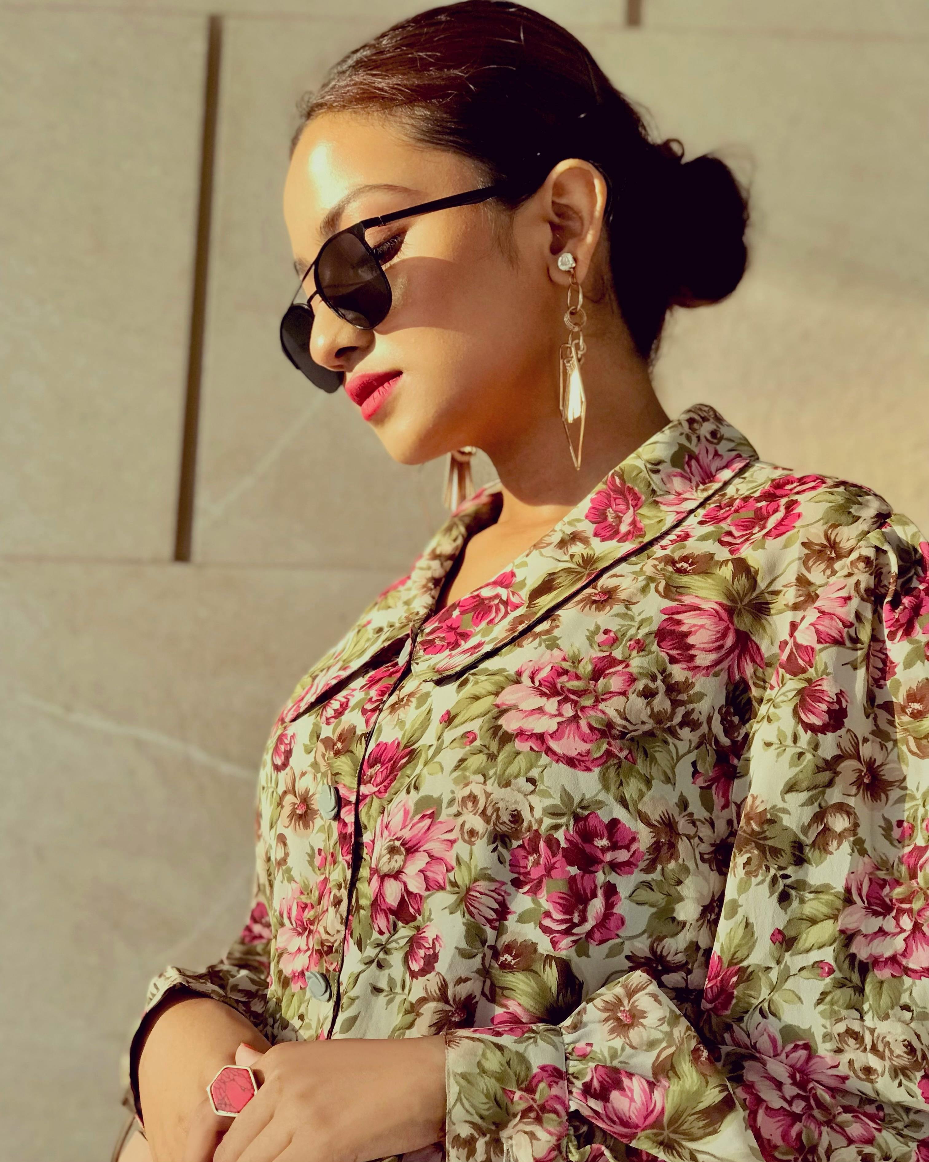 Stylish woman wearing floral top and sunglasses, exuding modern elegance.