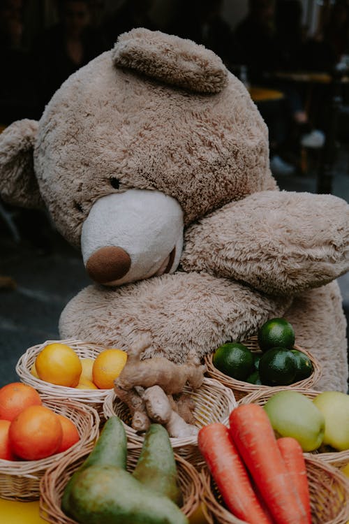 A Brown Teddy Bear Beside Fruits and Vegetables in Baskets