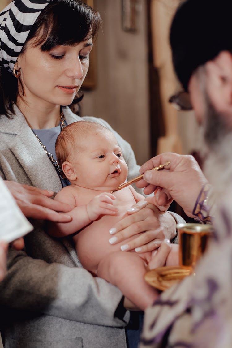 Naked Infant Being Baptized By Christian Priest