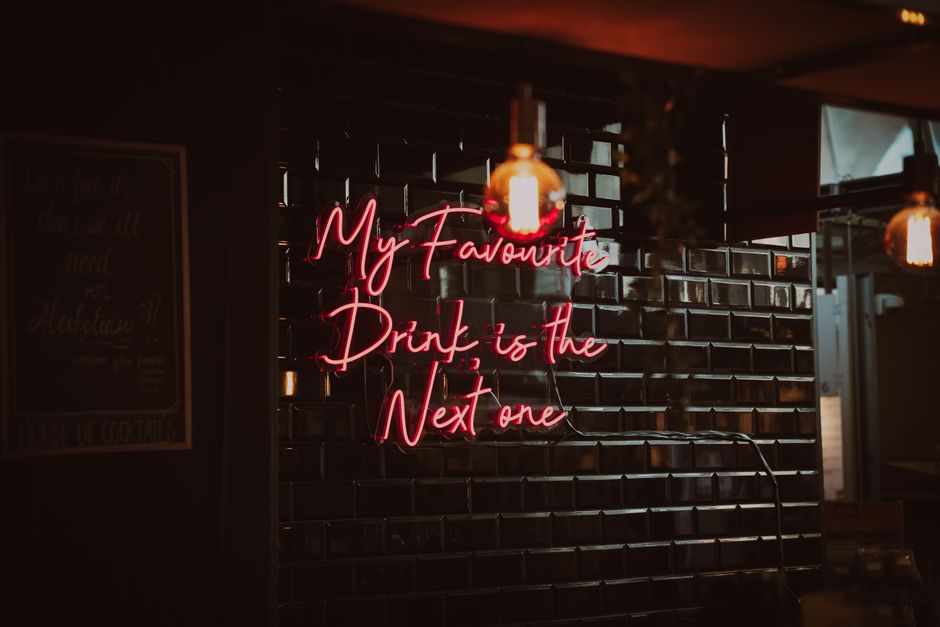 Stylish bar interior featuring a playful neon sign and industrial lighting.
