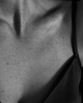 Close-up black and white image of a woman's collarbone highlighting skin texture and contrast.