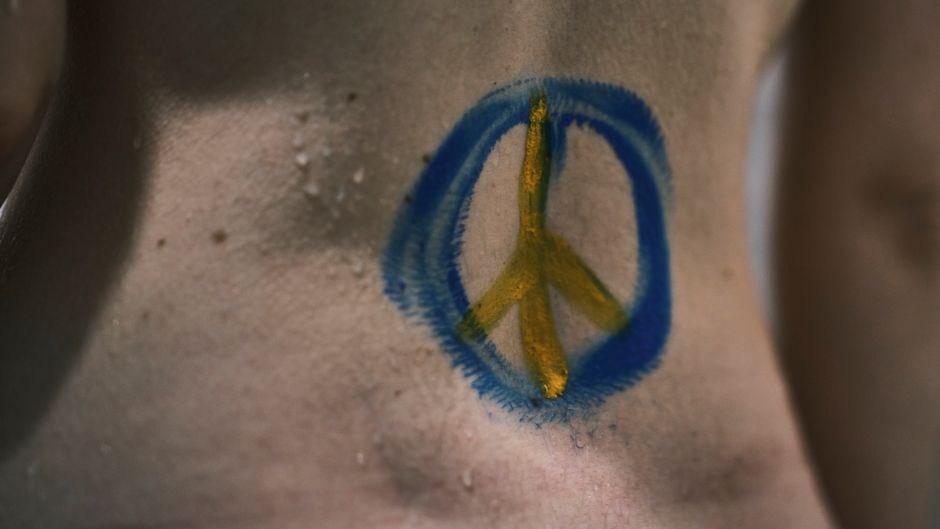 Fotomural Primer plano artístico de un colorido símbolo de paz pintado en una piel humana húmeda.