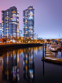 Stunning night view of Vancouver's waterfront with illuminated skyscrapers reflecting in the water.
