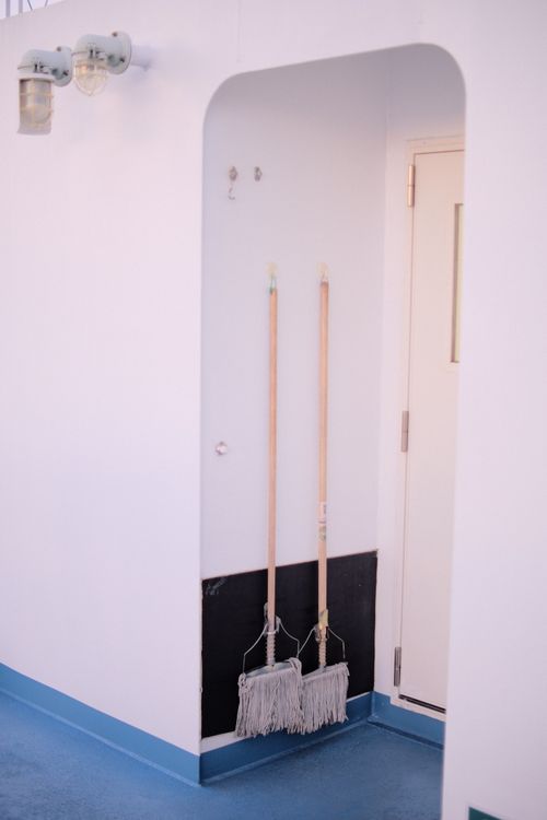 Free Two mops hanging in a clean, minimalist indoor space with blue flooring. Stock Photo