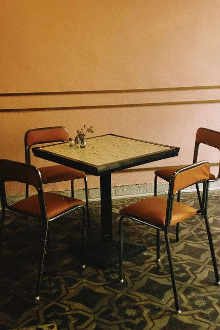 Vintage-style café setup with empty chairs and a square table in warm tones.