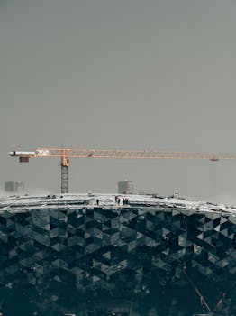 A snowy construction site with cranes and workers on a modern glass building in Novosibirsk.