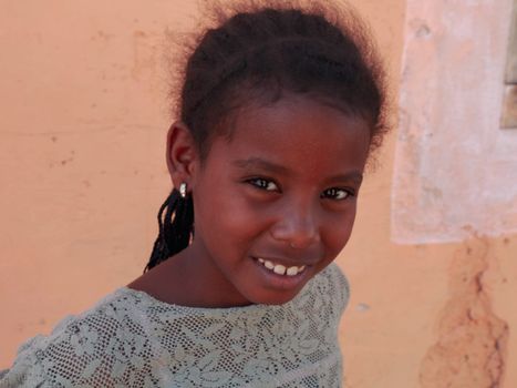 Close-up portrait of a smiling young girl wearing earrings.