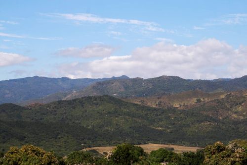 Free Stunning view of a mountain range beneath a blue sky, showcasing lush valleys and natural beauty. Stock Photo