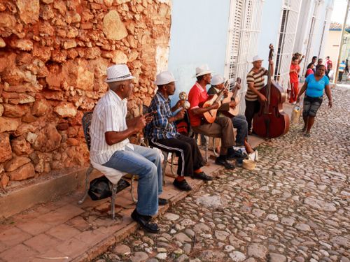 Free Street musicians play lively music with various instruments in a vibrant urban street. Stock Photo