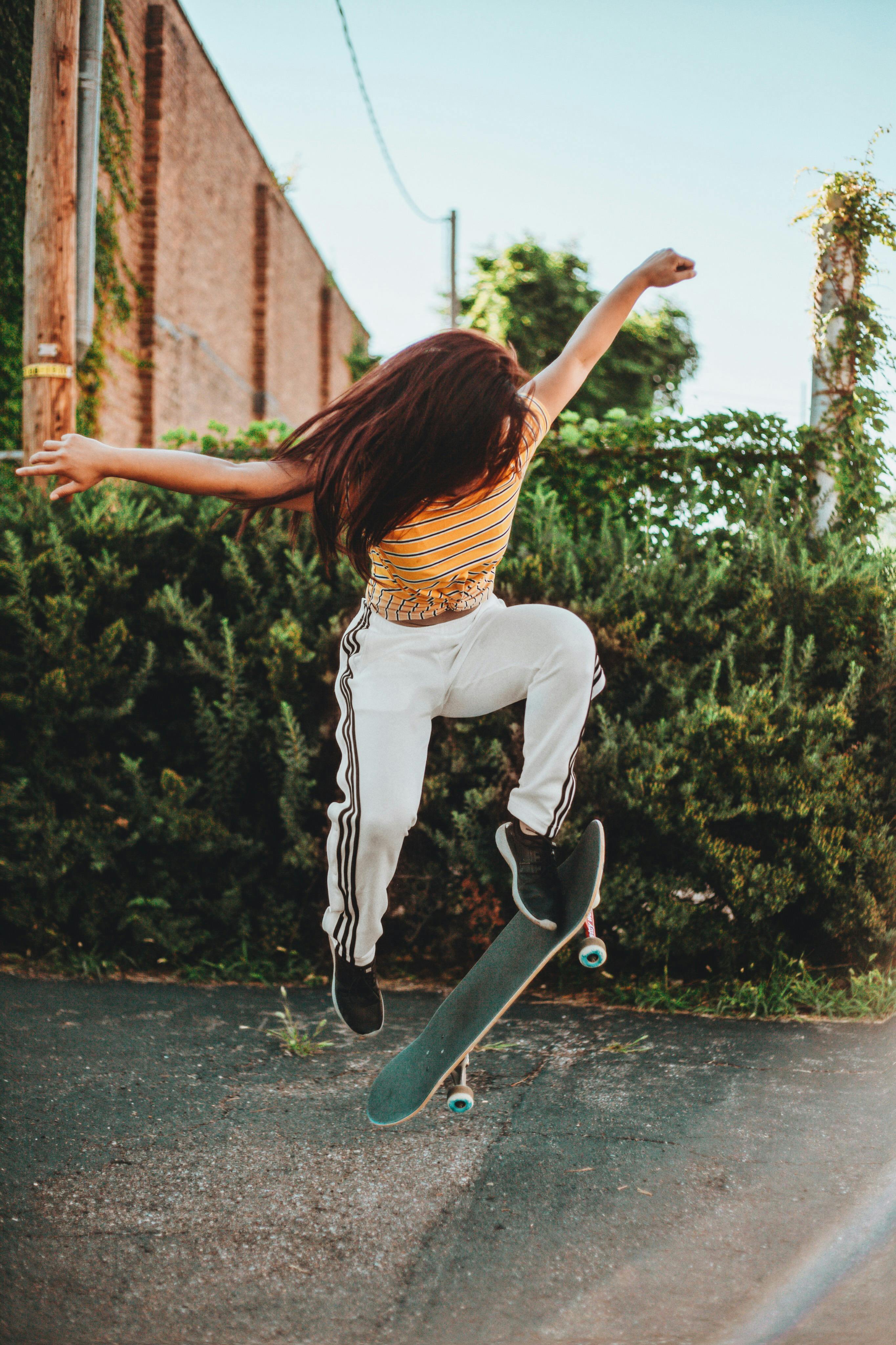 Woman in Striped Shirt and Jogging Pants on a Skateboard