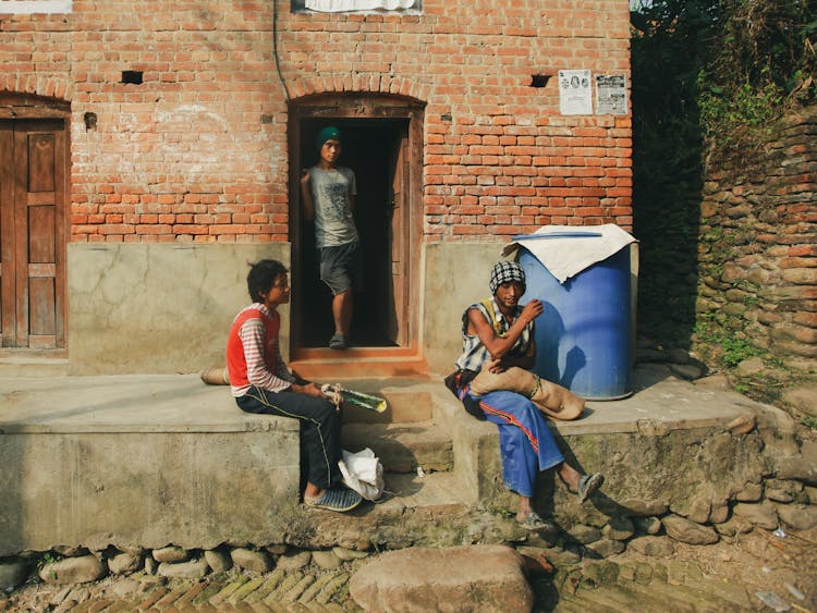 Men Sitting On Steps In Front Of House Entrance