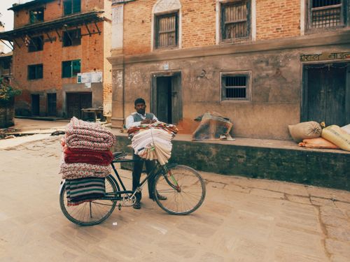Free A fabric merchant transporting goods on a bicycle in an urban setting. Stock Photo