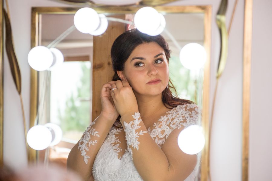 Bride adjusting earrings in a mirror