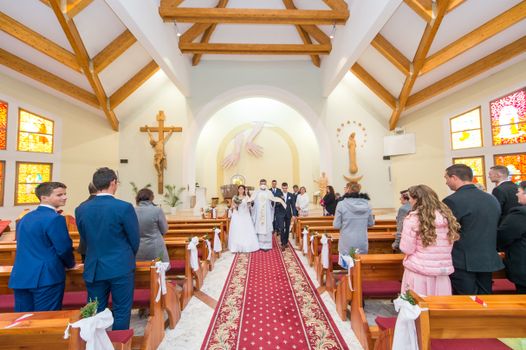 A bride and groom walk down the aisle after their wedding ceremony in a colorful church.