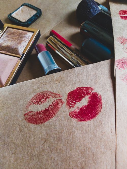 Free Artistic display of lipstick prints on paper surrounded by makeup items, emphasizing beauty and creativity. Stock Photo