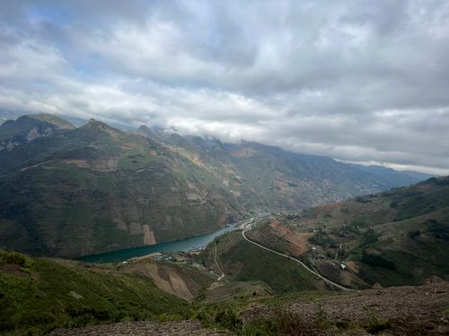 Free A stunning aerial view of a river winding through a lush mountain valley, under a cloudy sky. Stock Photo