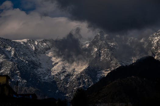Dramatic snow-capped mountains with ominous clouds over Shimla, India.