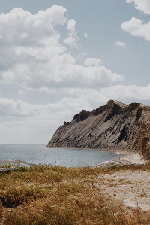Free Dramatic cliffs by the seaside with cloudy skies, perfect for travel and nature themes. Stock Photo