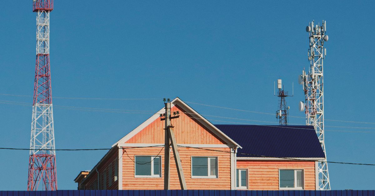 A contemporary house with communication towers under a clear blue sky, showcasing urban infrastructure.