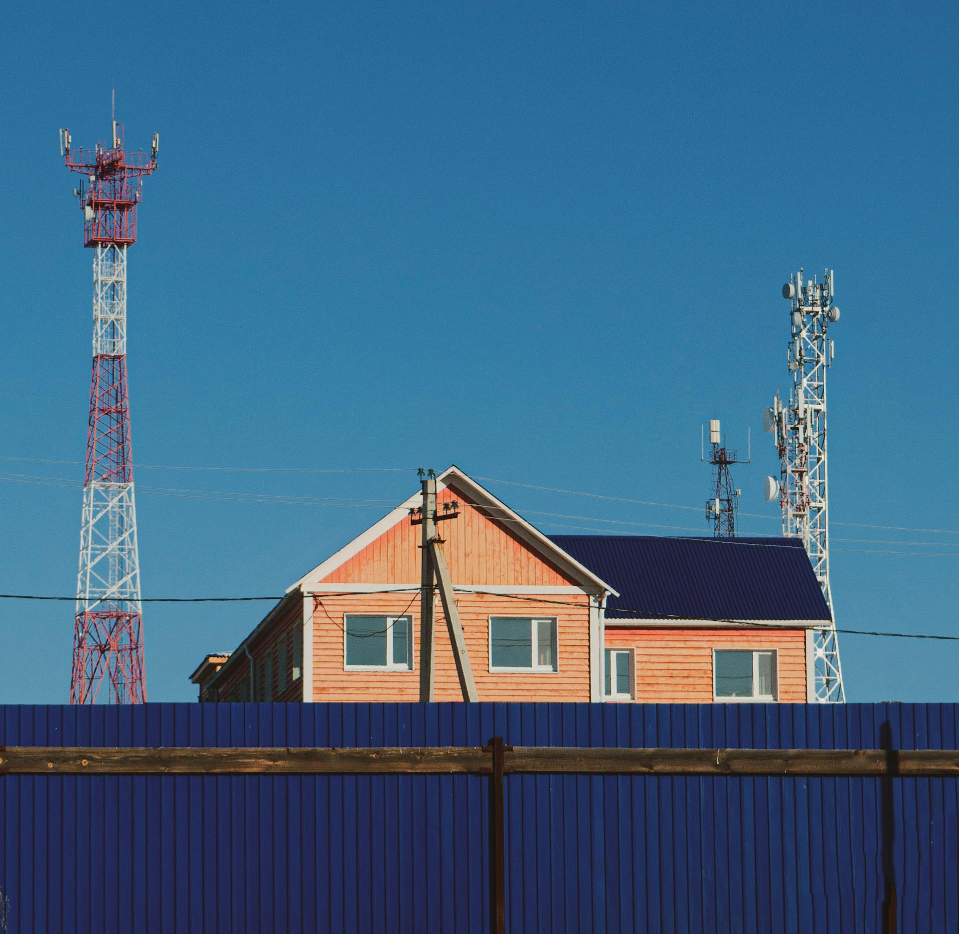 A contemporary house with communication towers under a clear blue sky, showcasing urban infrastructure.