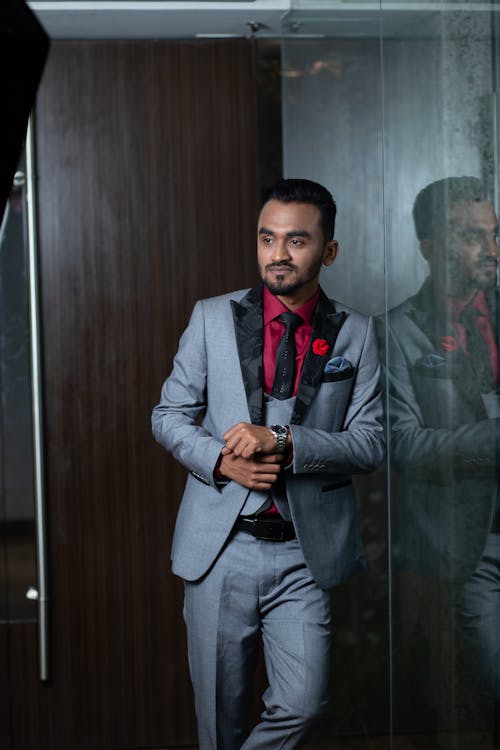 Man in Gray Suit Standing Beside Glass Wall