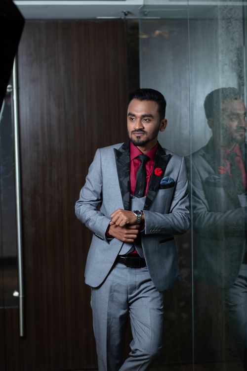 Free Stylish man in gray suit with red accents posed indoors by a glass wall. Stock Photo