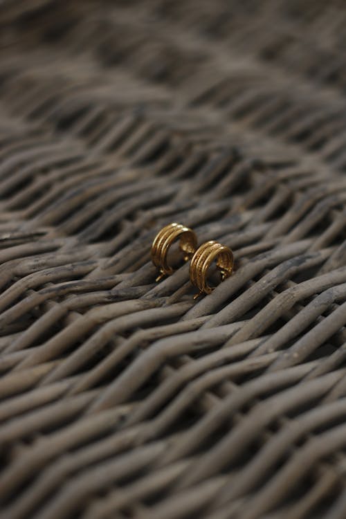 A Gold Earrings on a Woven Table