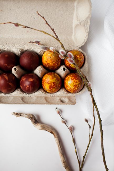 Colorful Easter eggs in a tray with decorative branches, perfect for seasonal themes.