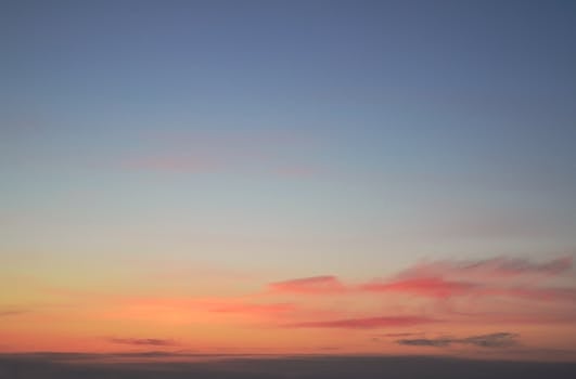 Serene sunset sky with vibrant hues of pink and orange against a clear blue background.