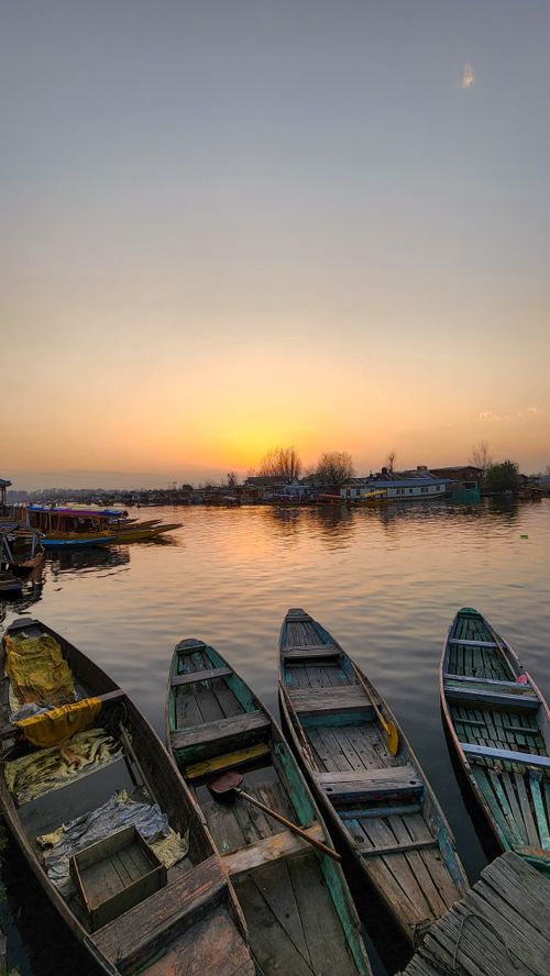 Free Picturesque view of wooden boats at sunset, reflecting peace and calm on the silent waters. Stock Photo