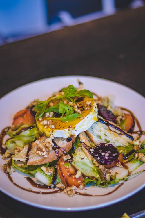 Free A vibrant gourmet salad with poached egg, fresh vegetables and nuts on a white plate. Stock Photo